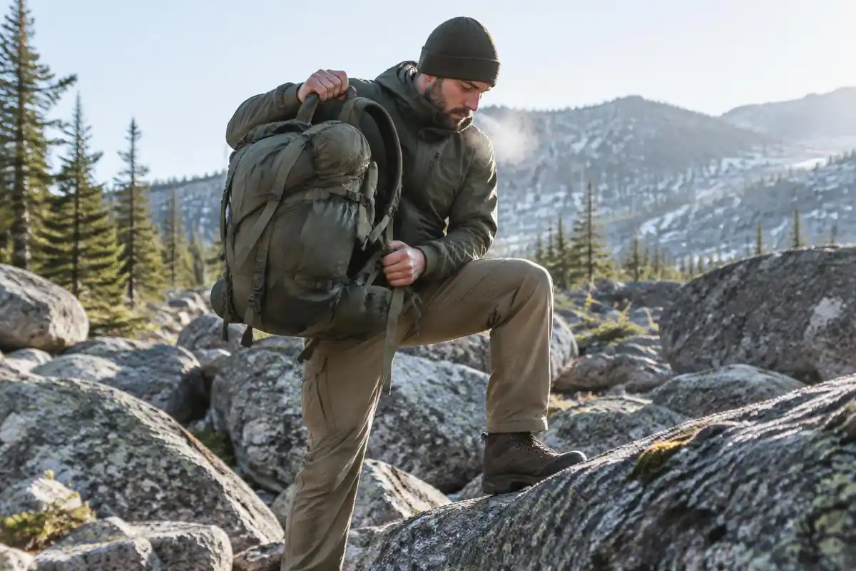 Hiker lifting a big pack onto a knee before shrugging it on