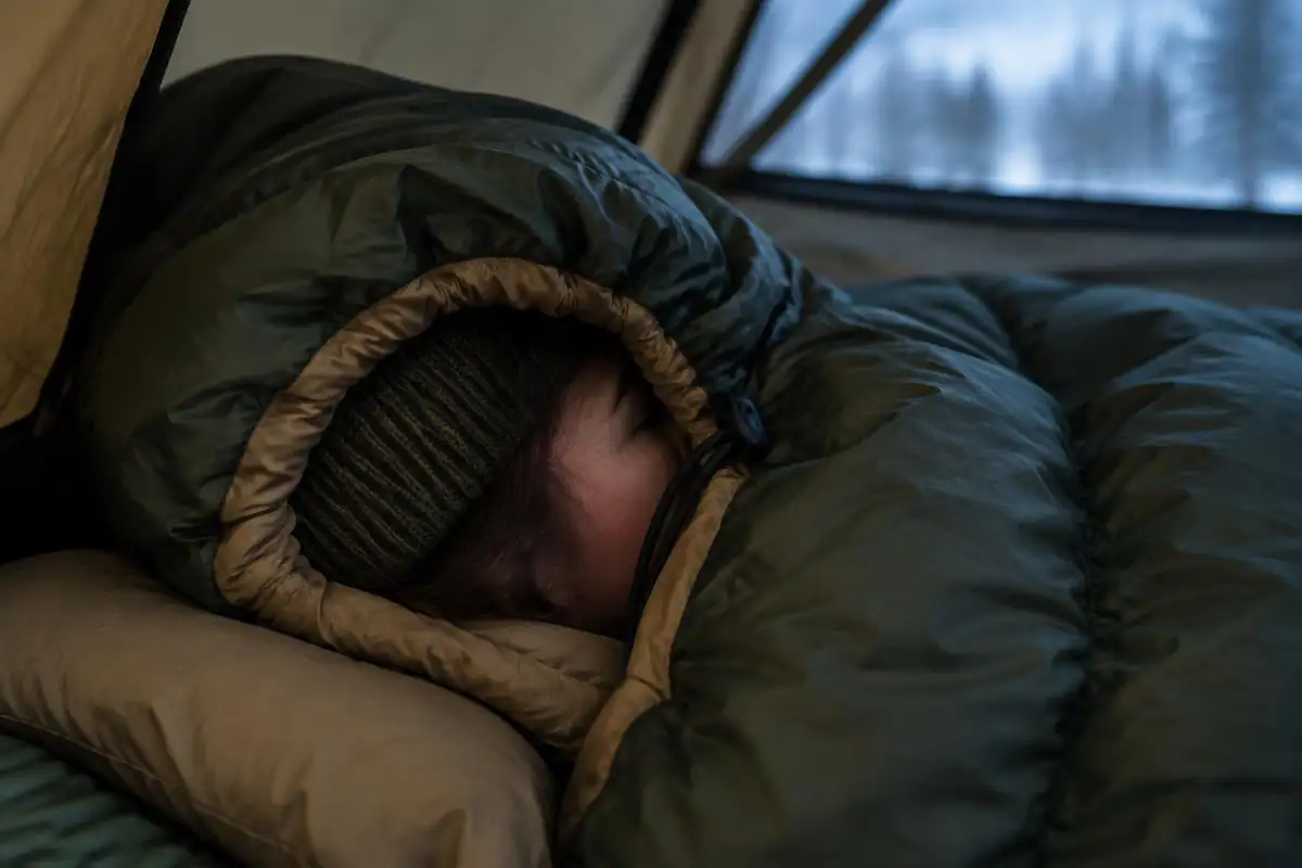 Insulated hood of a sleeping bag cinched around a hiker's face