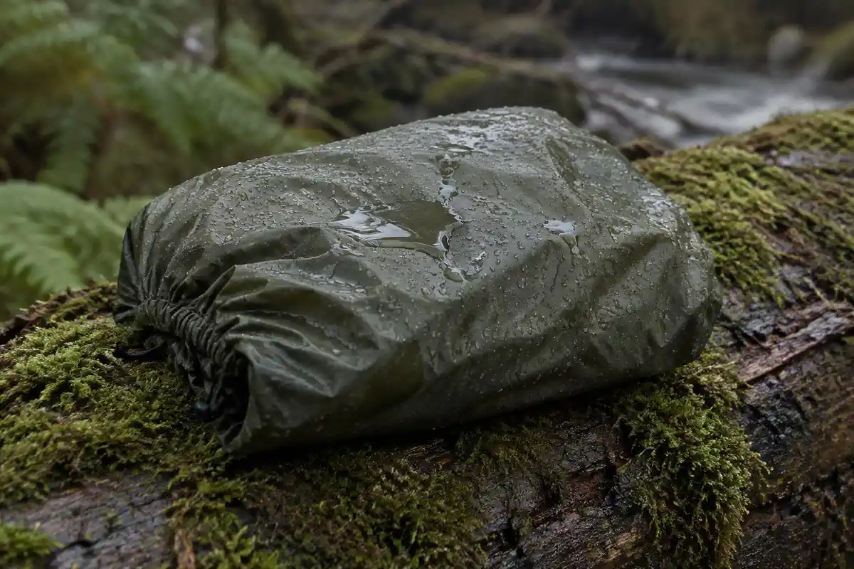 Rain pooling on a folded pack cover on a wet log