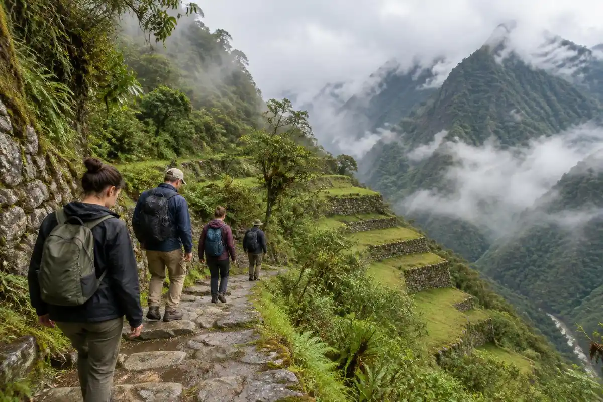 Small group of trekkers on a stone-terraced trail above misty green slopes