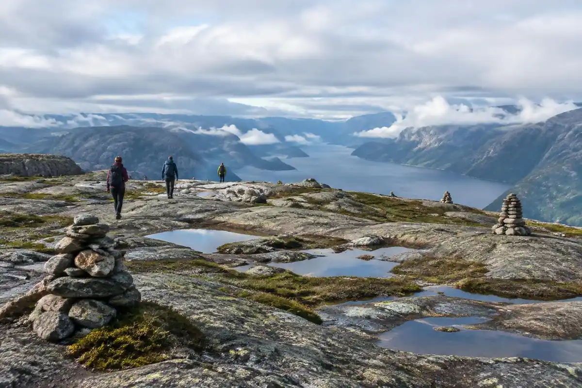 Flat-topped barren plateau with pools and cairns and a distant fjord
