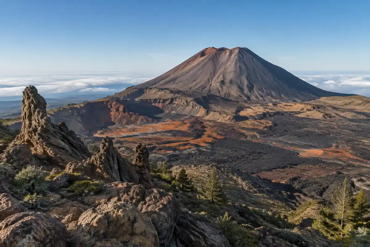 Giant volcanic cone above a caldera of orange and black lava fields and rock formations