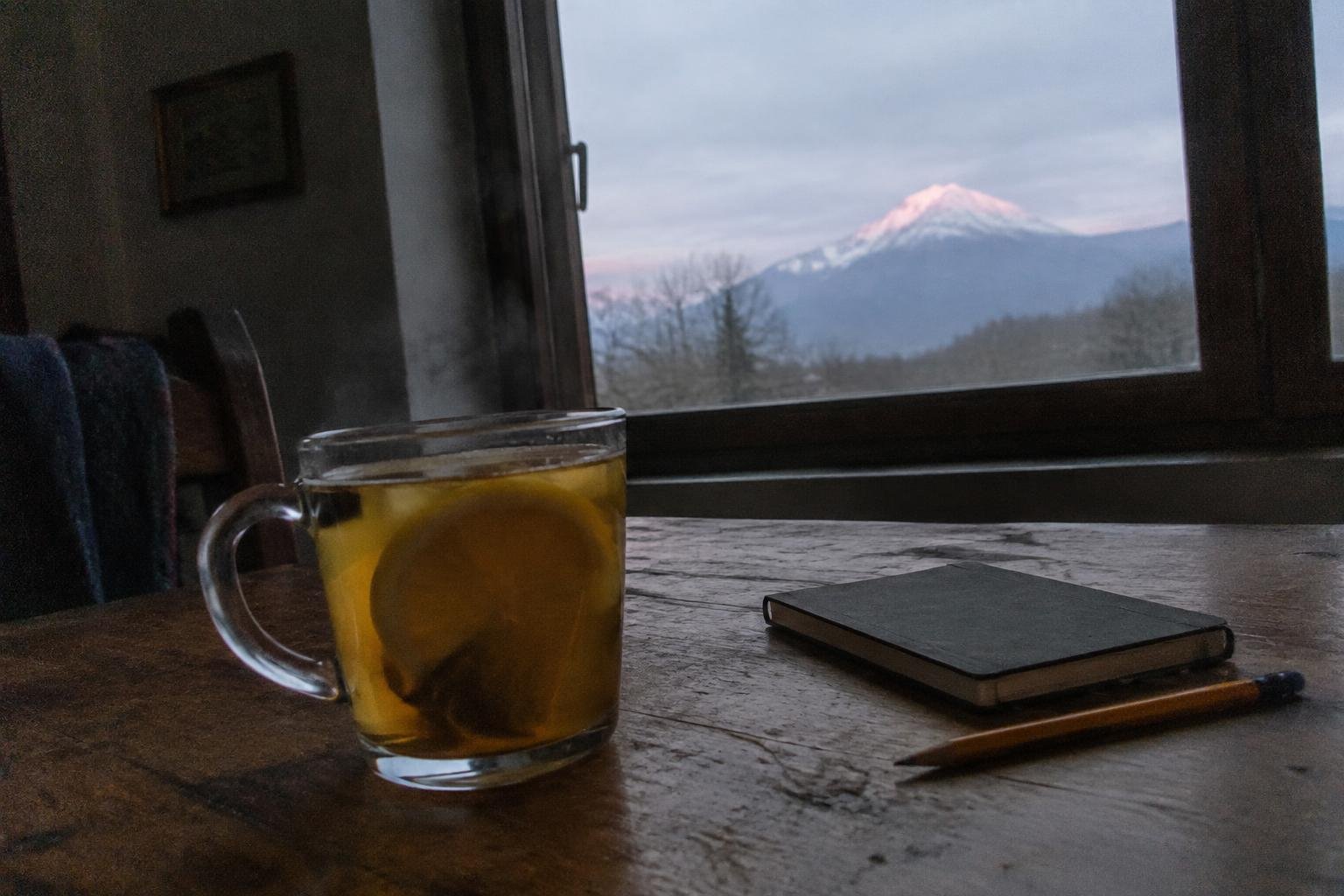 A glass of lemon tea on a wooden table beside a notebook