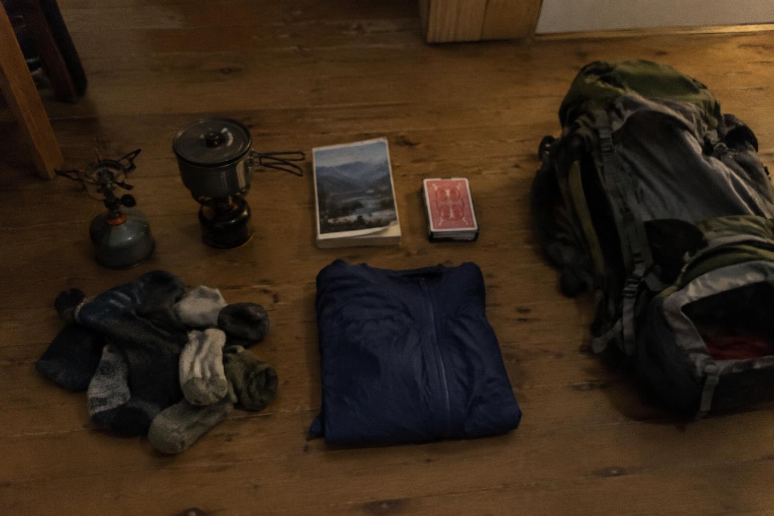 Gear laid out in rows on a lodge floor beside a half-packed pack