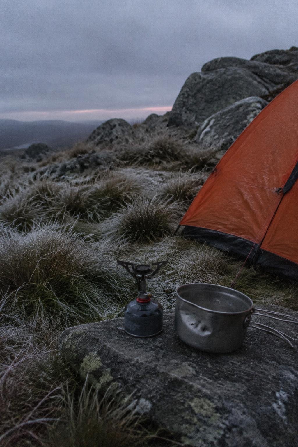 Cold camp stove and a frosty tussock beside a small tent at high camp